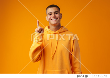 Handsome young man pointing to copy space on a yellow background 95840076