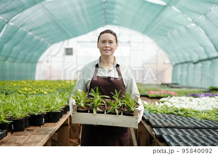 Photo realistic digital collage of mature woman holding flower seedlings 95840092