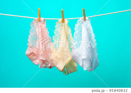 Female panties hanging on rope against blue studio background 95840632