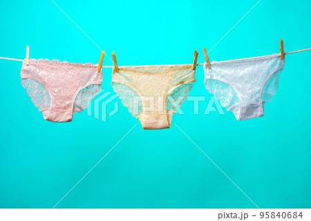 Female panties hanging on rope against blue studio background 95840684