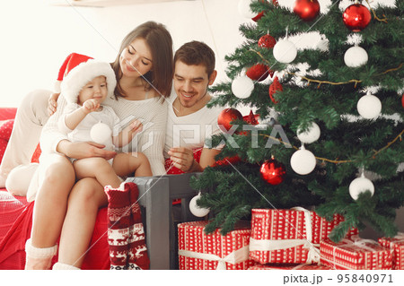 Mother in a white sweater. Family with christmas gifts. Child with parents in a christmas decorations. Mother in a white sweater. Family with christmas gifts. Child with parents in a christmas decorations. 95840971