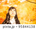秋の紅葉を楽しみながら眺めている女性 95844138