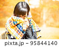 紅葉の中でブランケットに顔を埋める女性 95844140