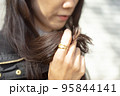 黒髪ロングの髪を触っている女性の手のクローズアップ 95844141