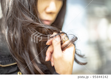 黒髪ロングの髪を触っている女性の手のクローズアップ 95844142