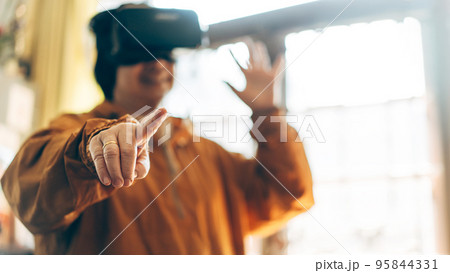 Focus on finger touch blur elder woman people wear virtual reality headset play game background. 95844331