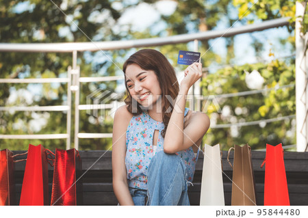 Young adult asian woman holding credit card and shopping bags. 95844480
