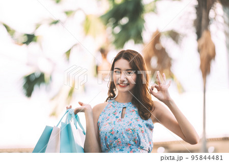 Happy young adult asian woman with shopping bags on day. 95844481