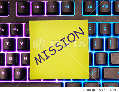 MISSION text on a yellow sticker on a glowing laptop keyboard MISSION text on a yellow sticker on a glowing laptop keyboard 95844639