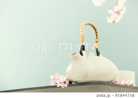 Cute teapot and spring cherry branches on blue background, copy space 95844738
