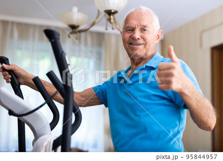 Senior man with elliptical trainer at home 95844957