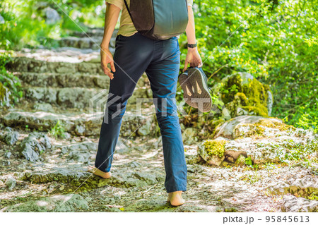 Man tourist climb barefoot the mountain to the Ostrog. It is a tradition to climb barefoot. Monastery of Ostrog, Serbian Orthodox Church situated against a vertical background, high up in the large 95845613