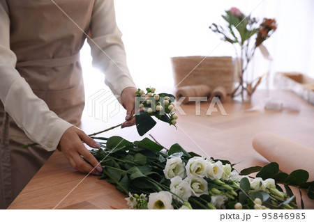 Florist making beautiful bouquet at table in workshop, closeup Florist making beautiful bouquet at table in workshop, closeup 95846985