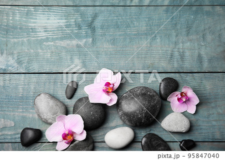 Stones with orchid flowers and space for text on blue wooden background, flat lay. Zen lifestyle Stones with orchid flowers and space for text on blue wooden background, flat lay. Zen lifestyle 95847040