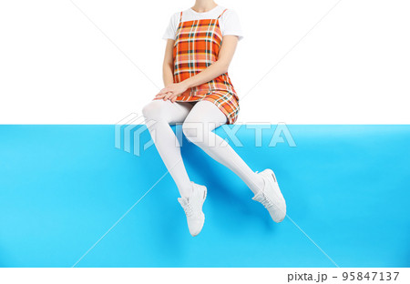Woman wearing white tights and stylish shoes sitting on color background, closeup Woman wearing white tights and stylish shoes sitting on color background, closeup 95847137