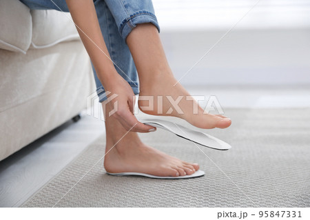 Woman fitting orthopedic insole at home, closeup Woman fitting orthopedic insole at home, closeup 95847331