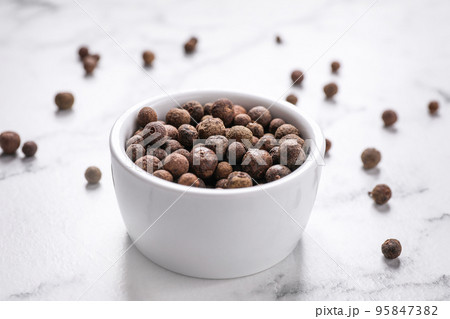 Black peppercorns in bowl on white marble table Black peppercorns in bowl on white marble table 95847382