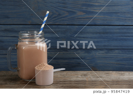 Protein shake and powder on wooden table, space for text 95847419