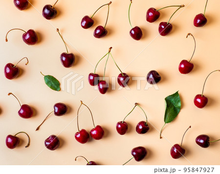 Fresh cherries scattered on yellow background 95847927