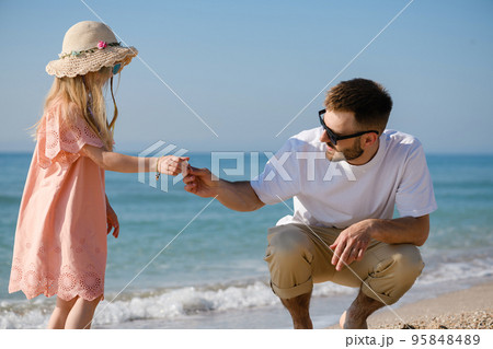 Father and daughter collect sea shells at beach 95848489