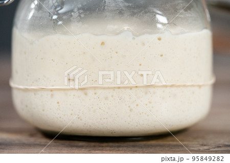 Feeding sourdough starter in a glass mason jar for baking artisan bread. Feeding sourdough starter in a glass mason jar for baking artisan bread. 95849282