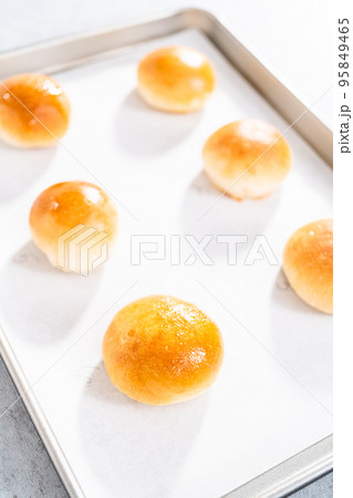 Freshly baked dinner rolls with an egg wash on a baking sheet lined with parchment paper. Freshly baked dinner rolls with an egg wash on a baking sheet lined with parchment paper. 95849465