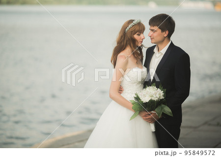 Beautiful romantic wedding couple of newlyweds hugging in park on sunset Beautiful romantic wedding couple of newlyweds hugging in park on sunset 95849572