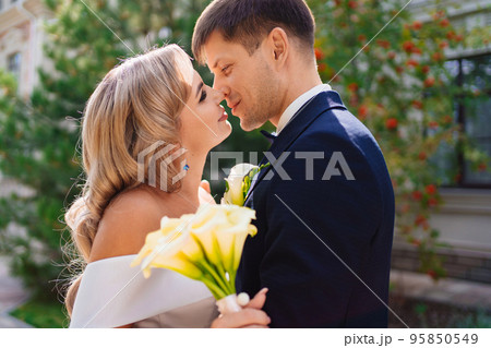 happy newlyweds. groom and bride in traditional wedding clothes kiss in park happy newlyweds. groom and bride in traditional wedding clothes kiss in park 95850549