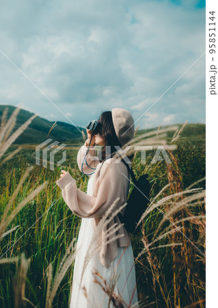 自然の中にカメラを持って佇む女性の写真 95851144