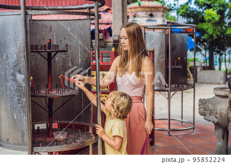 Incense sticks on joss stick pot are burning and smoke use for pay respect to the Buddha, Incense sticks in Mother and son hand and smoke use for pray respect to the Buddha in Buddhism life 95852224