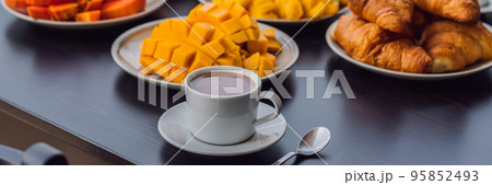 Breakfast table with coffee fruit and bread croisant on a balcony against the backdrop of the big city BANNER, long format Breakfast table with coffee fruit and bread croisant on a balcony against the backdrop of the big city BANNER, long format 95852493