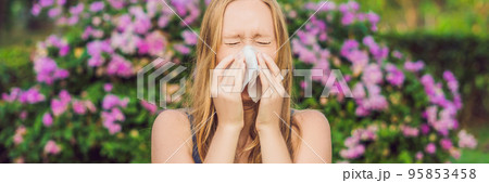 BANNER Pollen allergy concept. Young woman is going to sneeze. Flowering trees in background long format BANNER Pollen allergy concept. Young woman is going to sneeze. Flowering trees in background long format 95853458