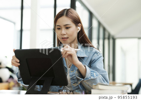 Young female student learning online using tablet. Young female student learning online using tablet. 95855193