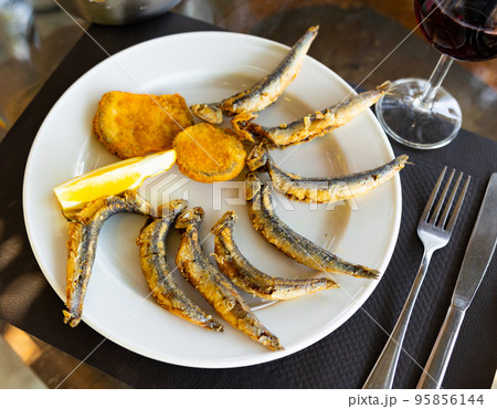 Pan-fried battered served on plate with vegetables and lemon Pan-fried battered served on plate with vegetables and lemon 95856144