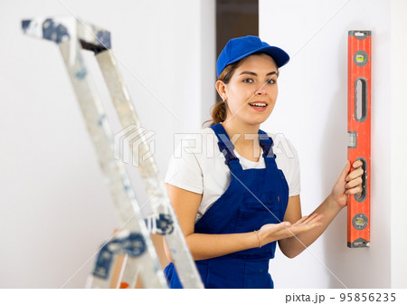 Woman worker measuring wall with spirit level 95856235
