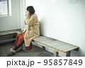 バスの待合室で手を温めているコートを着ている女性 95857849
