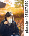 紅葉が綺麗なテラス席のカフェでお茶を飲む女性 95857850