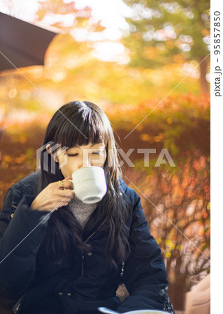 紅葉が綺麗なテラス席のカフェでお茶を飲む女性 紅葉が綺麗なテラス席のカフェでお茶を飲む女性 95857850