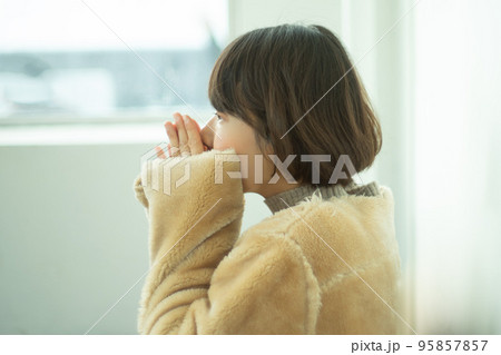 バスの待合室で手を温めているコートを着ている女性 バスの待合室で手を温めているコートを着ている女性 95857857