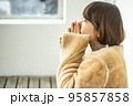 バスの待合室で手を温めているコートを着ている女性 95857858