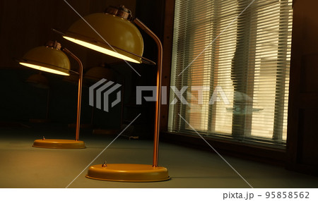 Yellow desk lamp on a beautiful green table Near the window. 95858562