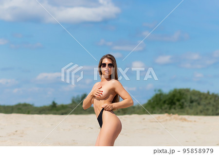 Cropped image of woman standing on the beach without swimsuit (holding bra  on her hand) - concept of nudist beach, FKK, topless and freedom Stock  Photo