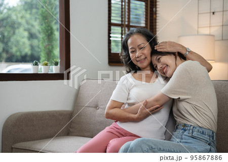 smiling grownup daughter hugging older mother. two generations concept, beautiful young woman embracing mature woman, posing for photo together. 95867886