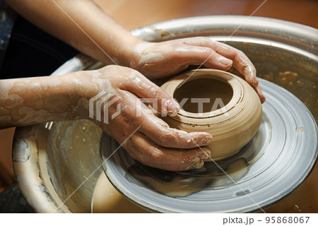 Master's hands mold a jug on a potter's wheel Master's hands mold a jug on a potter's wheel 95868067