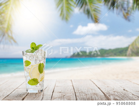 Mojito cocktail on wooden table in front of sunny sea Mojito cocktail on wooden table in front of sunny sea 95868808