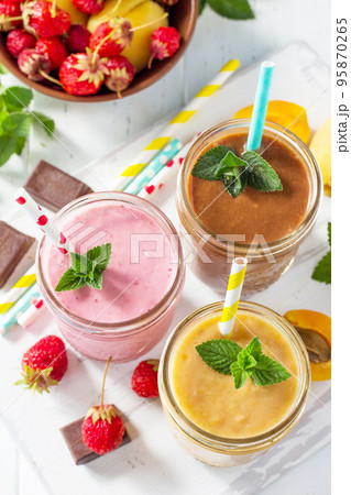 Strawberry, chocolate and apricot milkshake or smoothies on a white wooden background. Healthy juicy vitamin drink diet or vegan food concept. 95870265