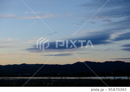 夕日に染まる宮島沼とマガンの群れ 95870365