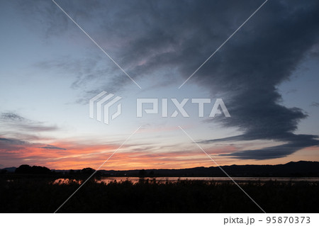 夕日に染まる宮島沼とマガンの群れ 95870373