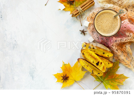 Autumn background baking. Freshly baked raisins and cinnamon biscotti and a cup of cappuccino coffee on light slate or slate background. Top view flat lay background, copy space. Autumn background baking. Freshly baked raisins and cinnamon biscotti and a cup of cappuccino coffee on light slate or slate background. Top view flat lay background, copy space. 95870391