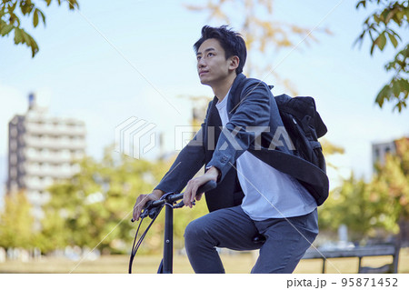 自転車に乗るジャケットを着た若い日本人の男性 95871452